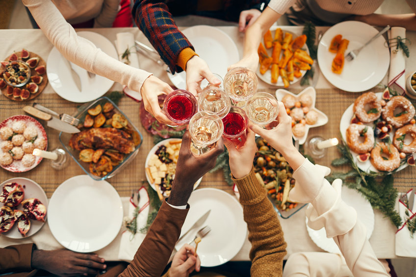 people raising glasses over festive dinner table while celebrating Christmas with friends
