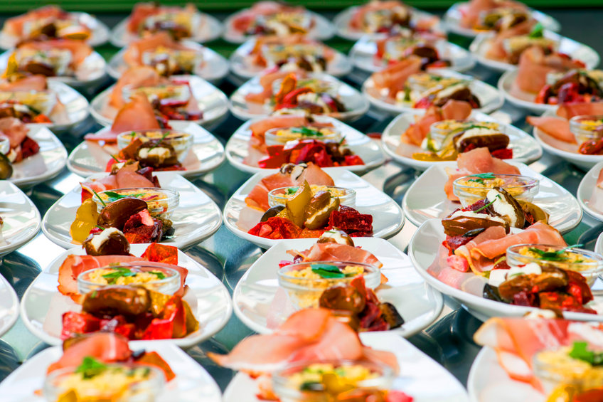 Caterer puts the starter on many plates with vegetables and antipasti